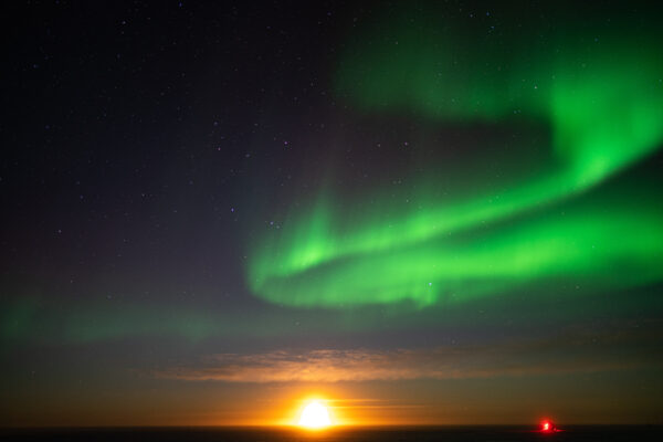 Moonrise over the South Pole with green auroras.