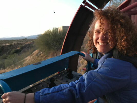 A woman with curly hair smiling on a manlift