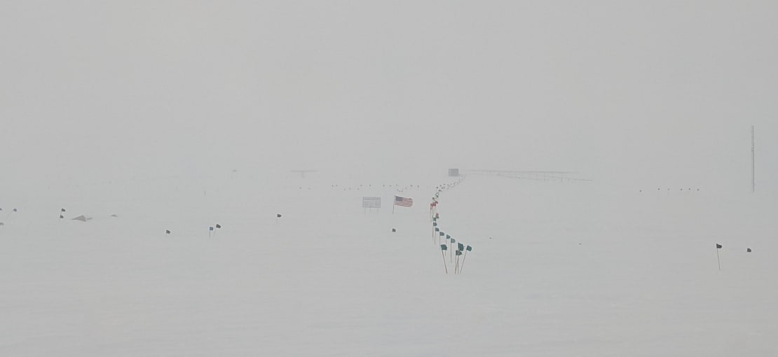 Low visibility view of a flagline near the geographic South Pole sign.