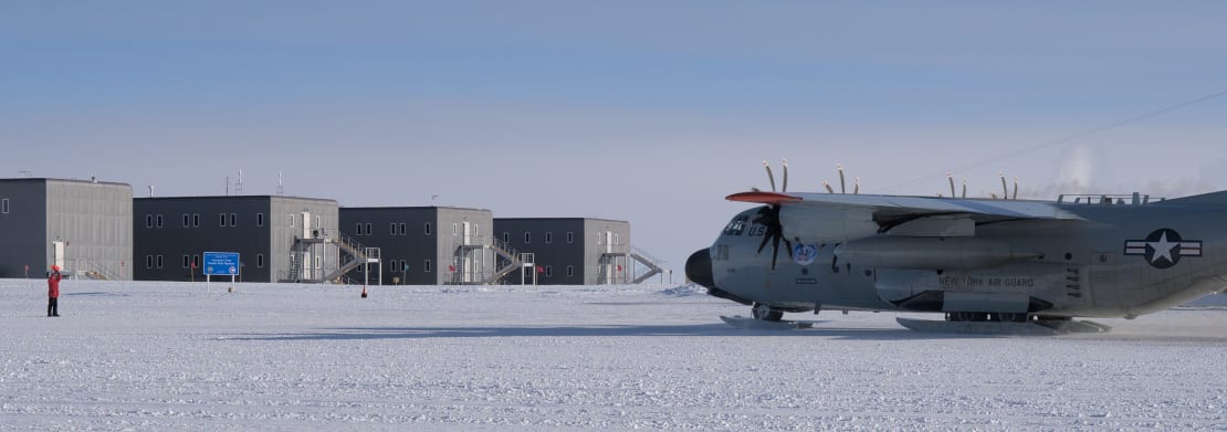 Someone marshalling a large plane in front of the South Pole station.