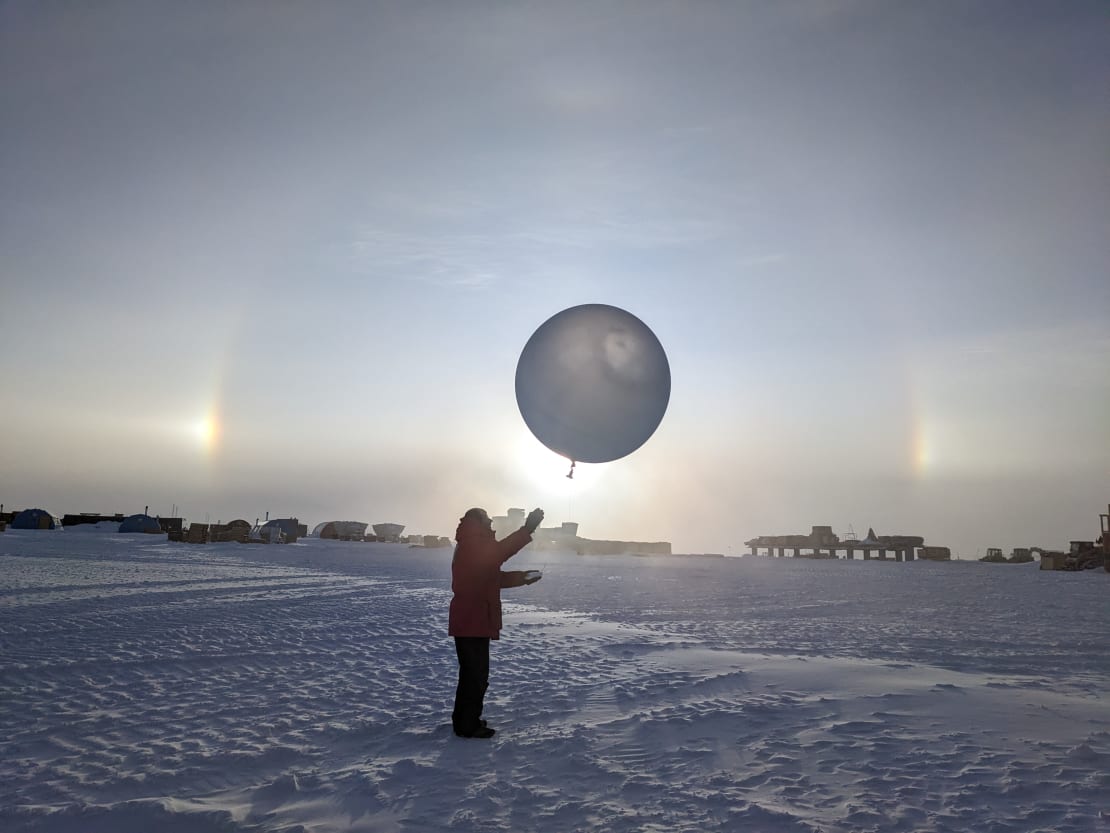 Winterover launching a weather balloon with sundog in background.