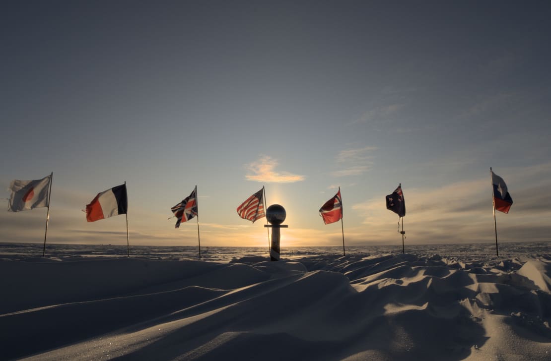 The ceremonial South Pole at sunset, with sun blocked by mirrored Pole marker.