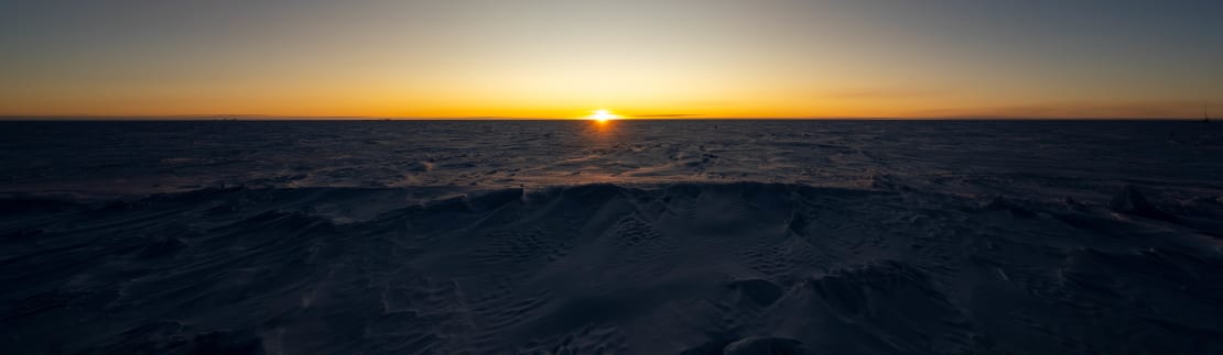 The sun setting on the horizon, with yellow stretching across the full horizon.