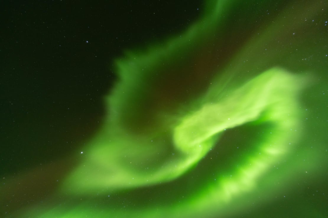 Bright green auroras making an S-shape in the sky.