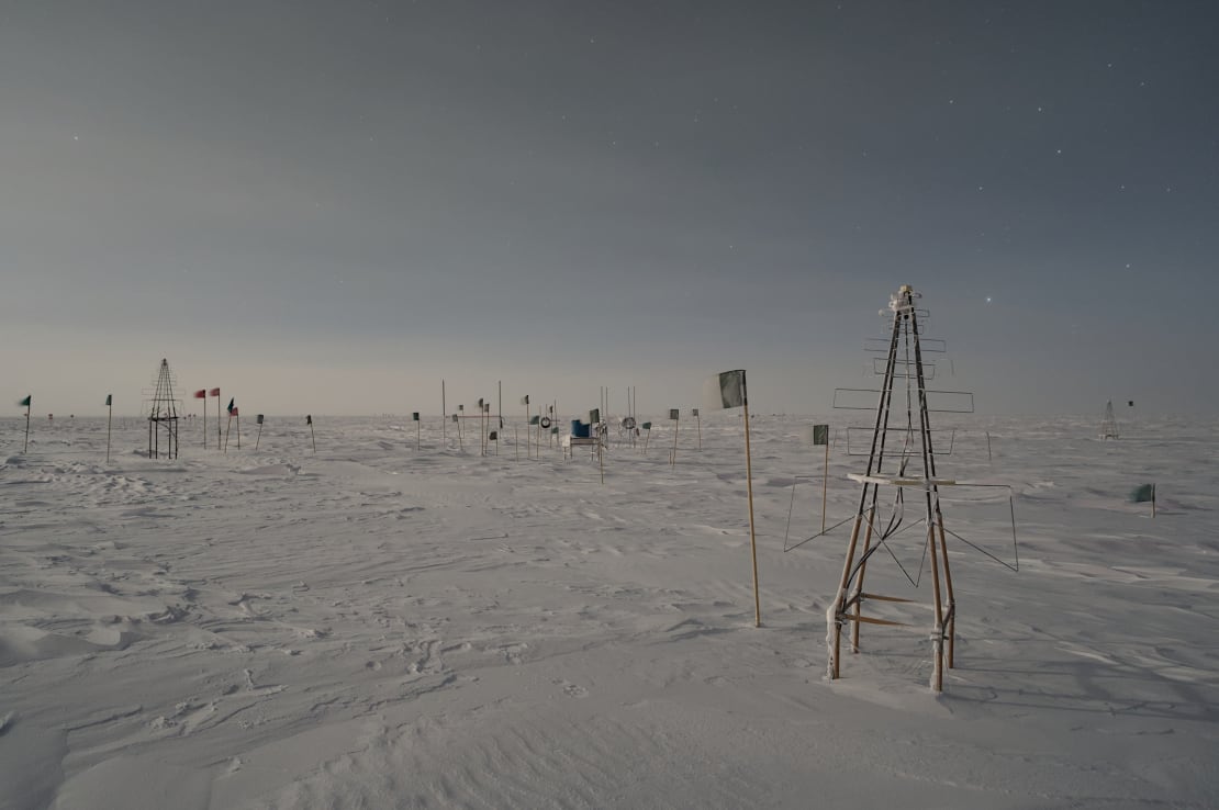 Flags and antennas dotting the barren South Pole landscape.