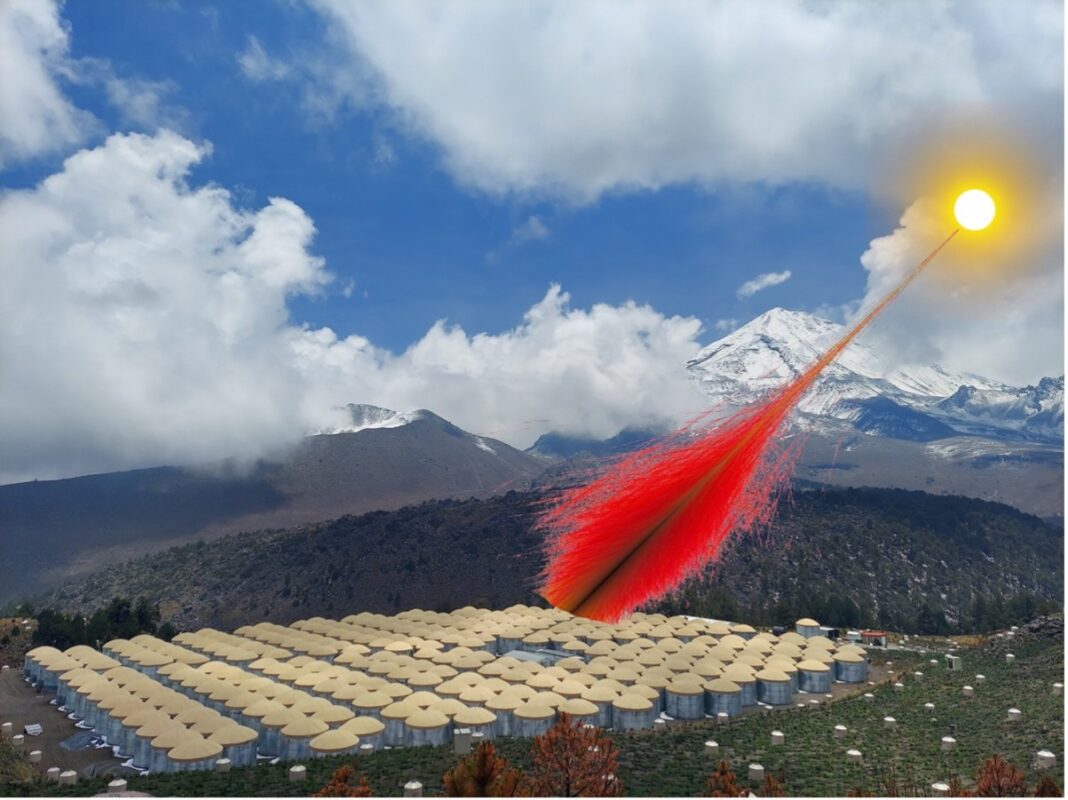 A composite image shows a photograph of the High-Altitude Water Cherenkov Observatory in Mexico. The observatory is a grid of 300 water tanks with steel walls and tan caps. A portion of these tanks are being struck by red lines, showing the trajectory of particles generated by high-energy gamma rays from the sun.