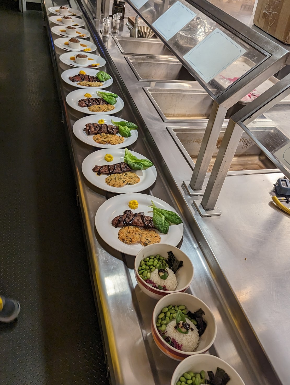 Long view of multiple plates of three course meal lined up and ready for judging.