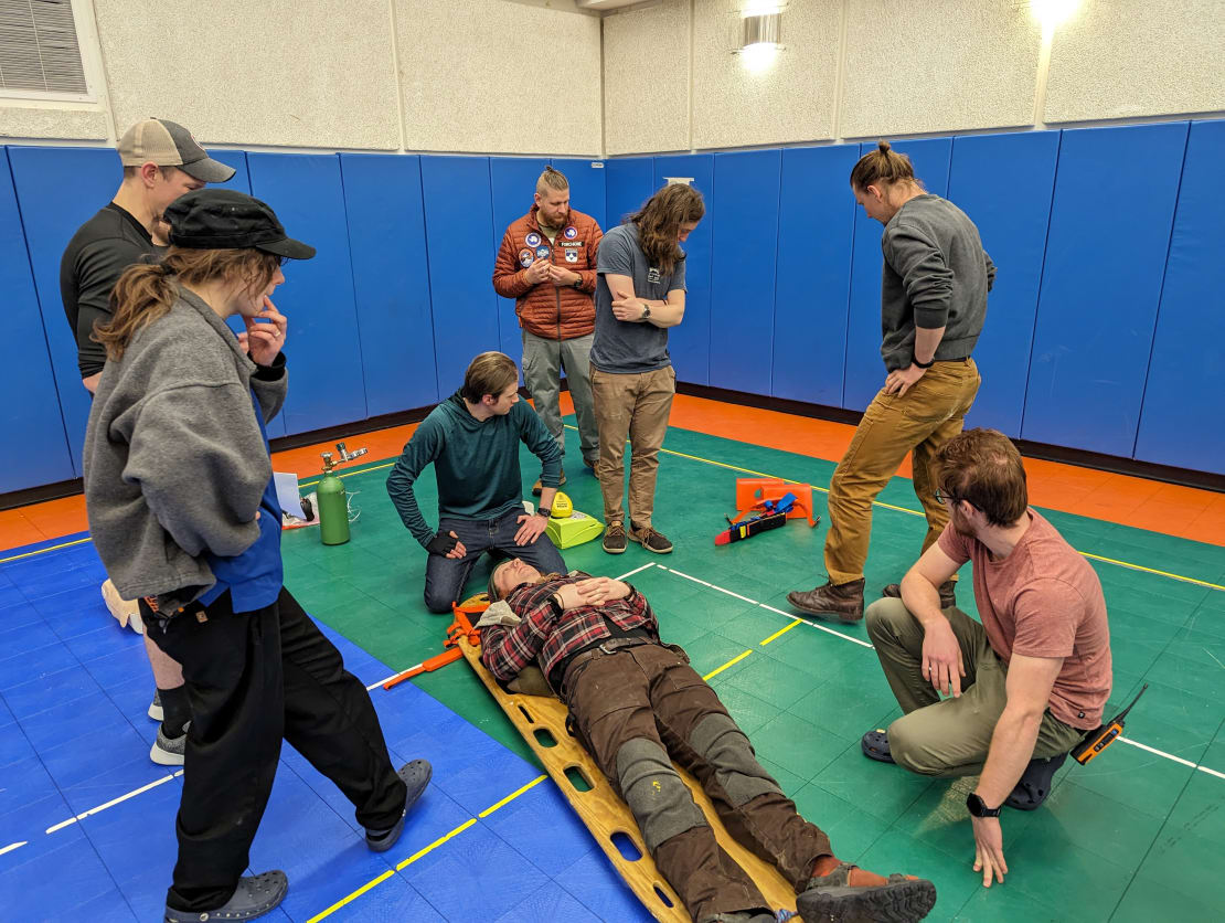 Several people gathered around a person on a flatboard in emergency response activity.