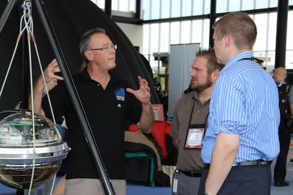 A man talking to two other men in front of a digital optical module