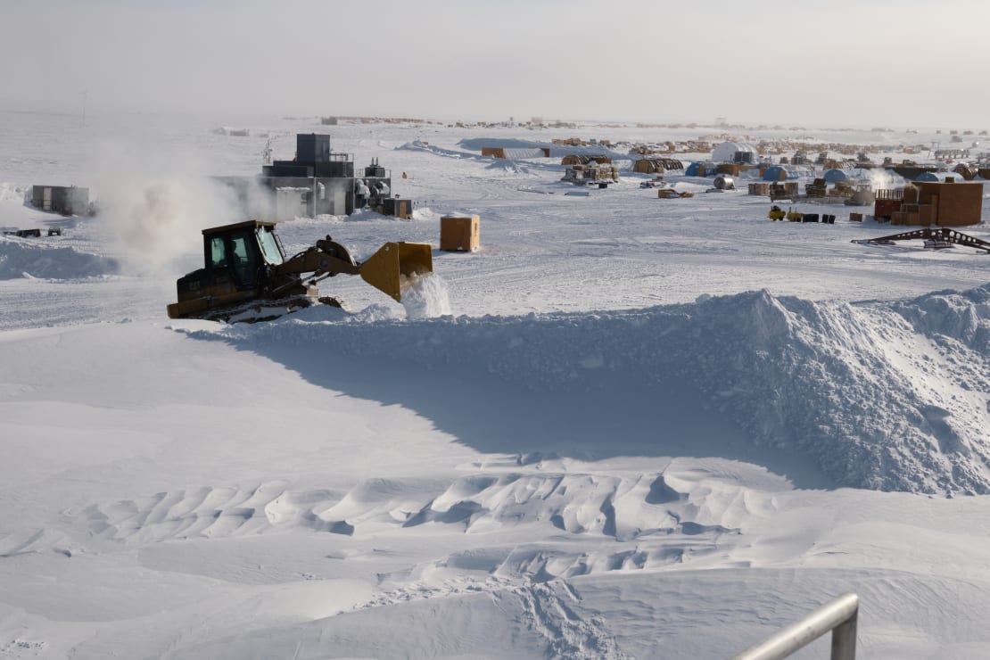 A snow vehicle with a front plow moving snow.